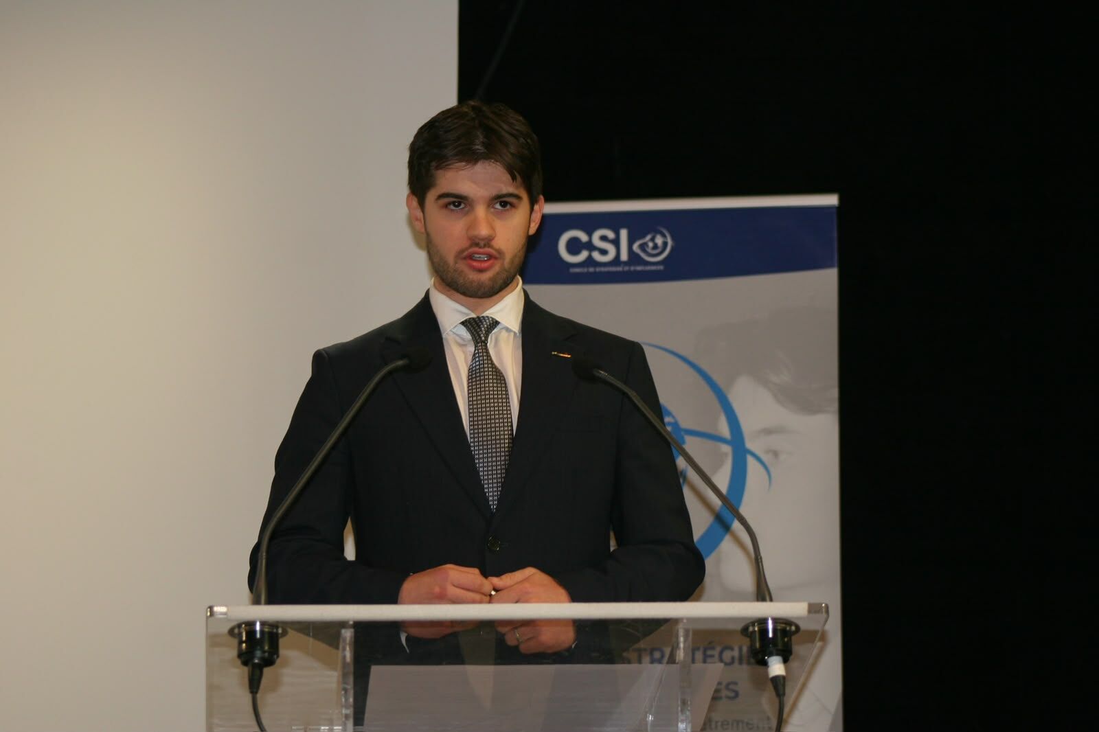 Un jeune intervenant à la tribune devant la bannière du CSI